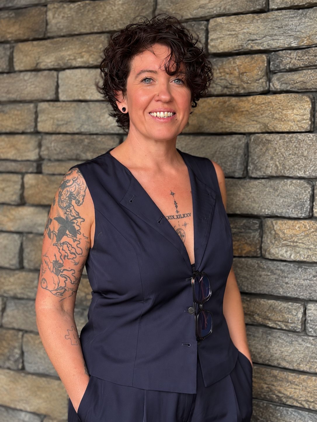 Ruth Maxwell, founder of Alternative Healings, smiling against a stone wall